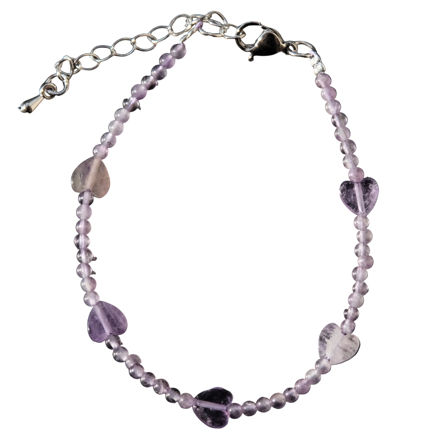 Bracelet with purple beads and heart-shaped stones on a dark surface