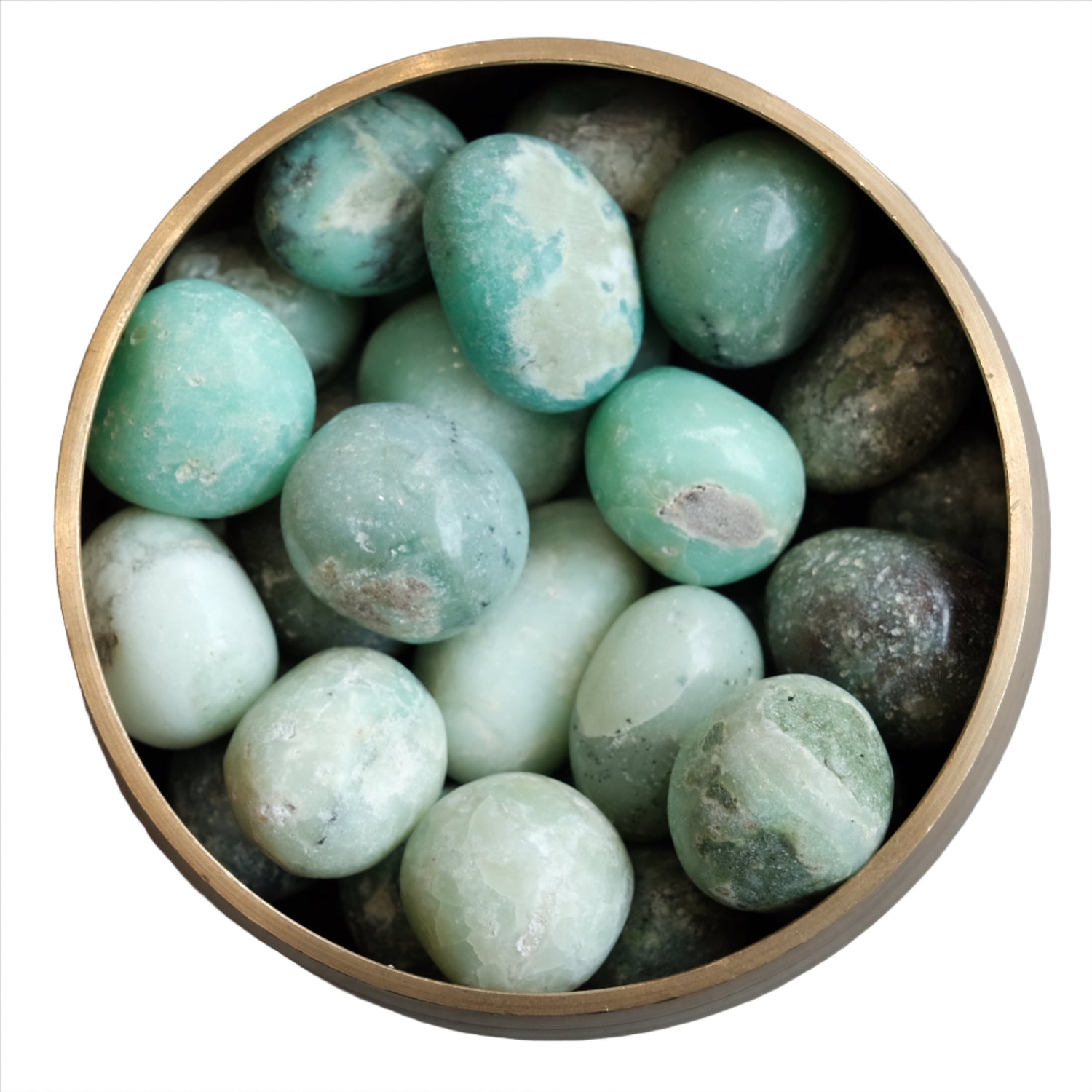 Chrysoprase tumbled stones in a brass bowl, promoting creativity and emotional healing.