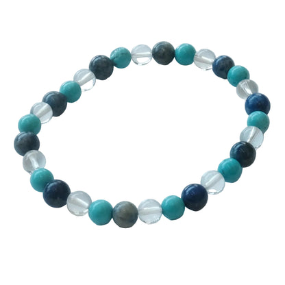 A beaded stretch bracelet featuring round turquoise, dark blue, gray, and clear faceted beads, arranged in a circular shape on a light gray background.