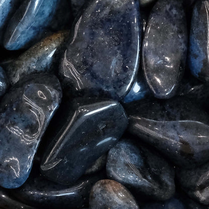 Dumortierite tumbled stones with deep blue hues, promoting calmness, self-confidence, and inner strength. Ideal for energy harmonization.