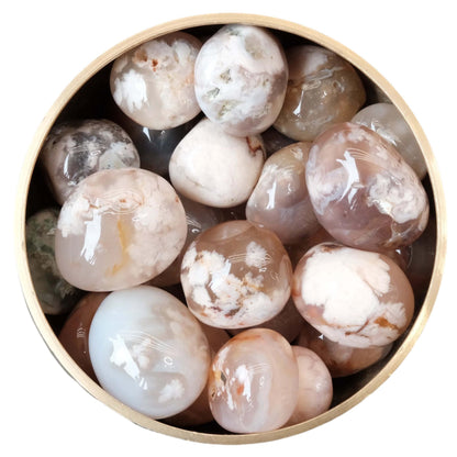 Flower Agate tumbled stones in a bowl, showcasing their light pink hues and delicate inclusions.