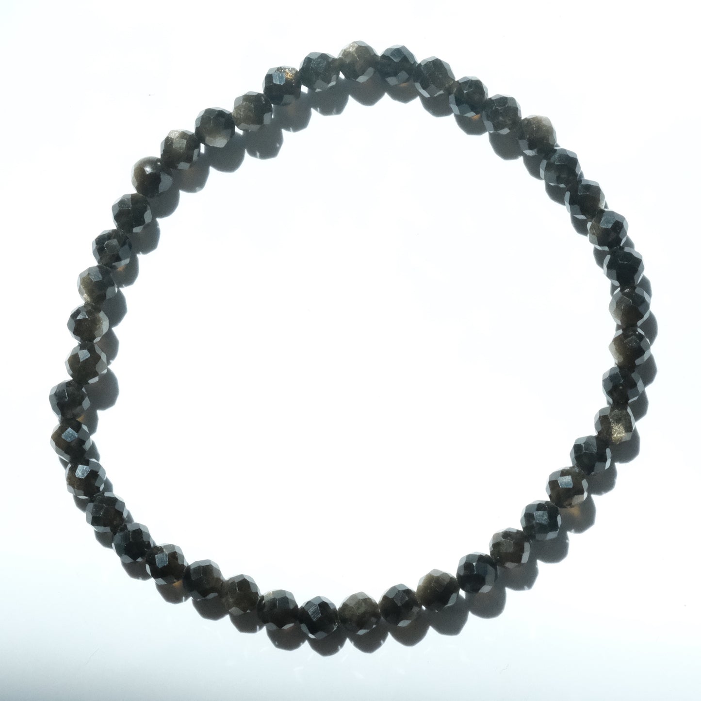 A beaded stretch bracelet made of faceted dark gray beads, arranged in a circular shape against a plain white background.