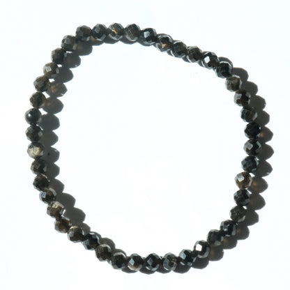 A beaded stretch bracelet made of faceted dark gray to black beads, arranged in a circle on a plain white background.