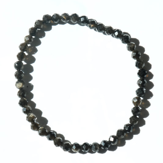 A beaded stretch bracelet made of faceted dark gray to black beads, arranged in a circle on a plain white background.