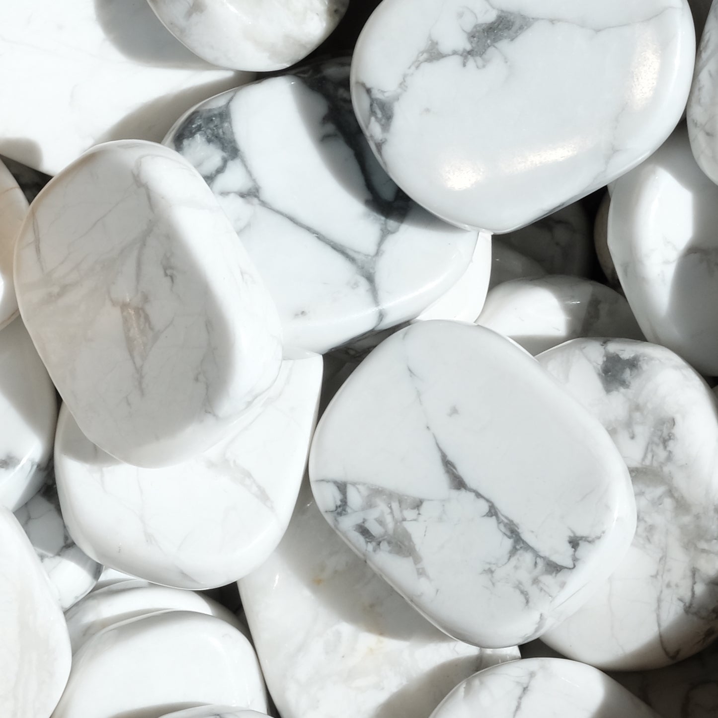 Collection of smooth Howlite tumbled flat stones with calming gray marbling, used for stress reduction and emotional healing.