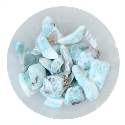 Collection of polished Larimar tumbled stones in a white bowl, known for healing and balancing energies.