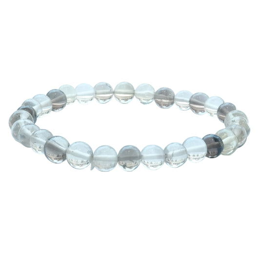 A beaded stretch bracelet made of clear, round glass or crystal beads with some translucent gray and dark gray accents, displayed on a light blue-white surface.