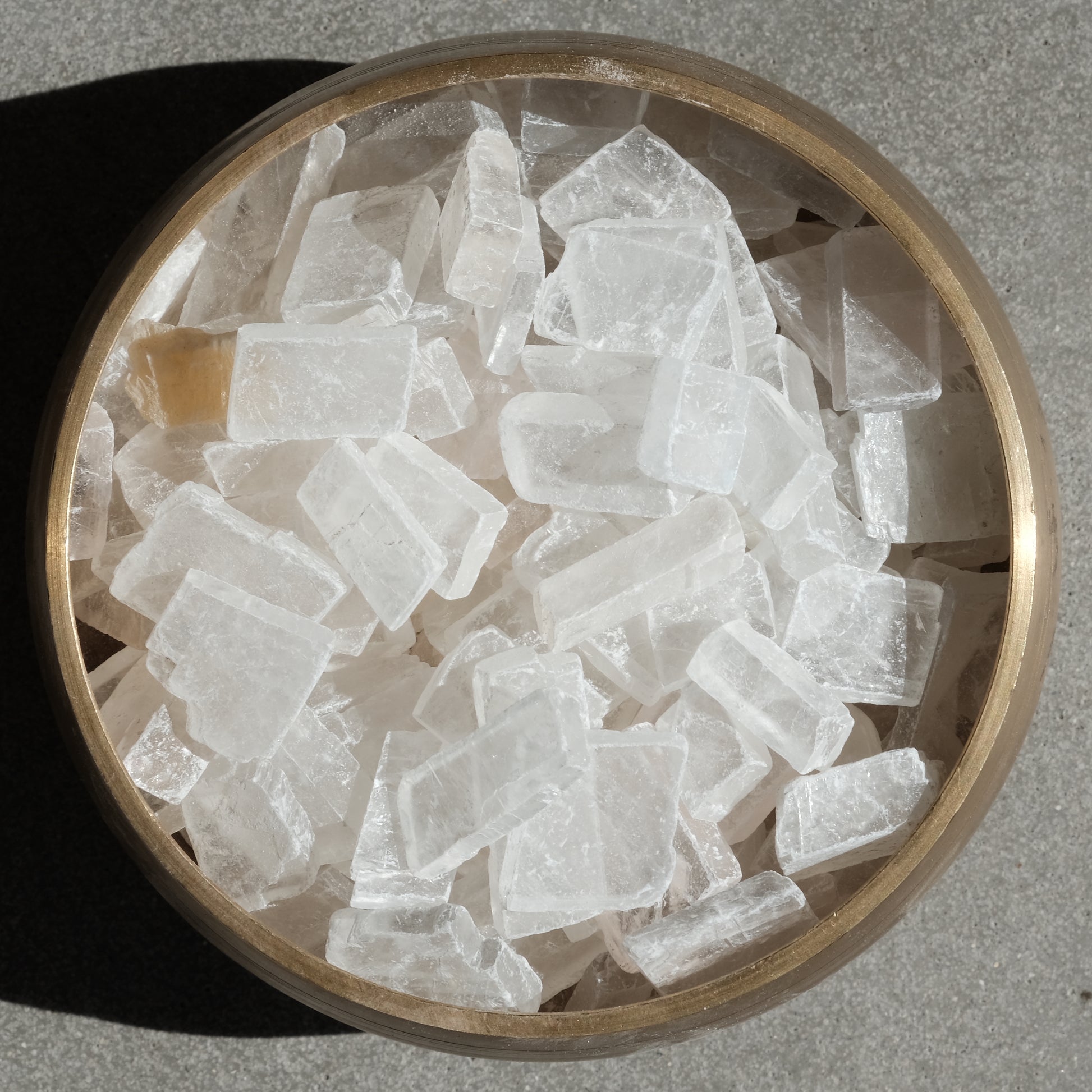 Optical Calcite Iceland Spar raw crystals in a wooden bowl, known for enhancing communication and clearing negative energy.