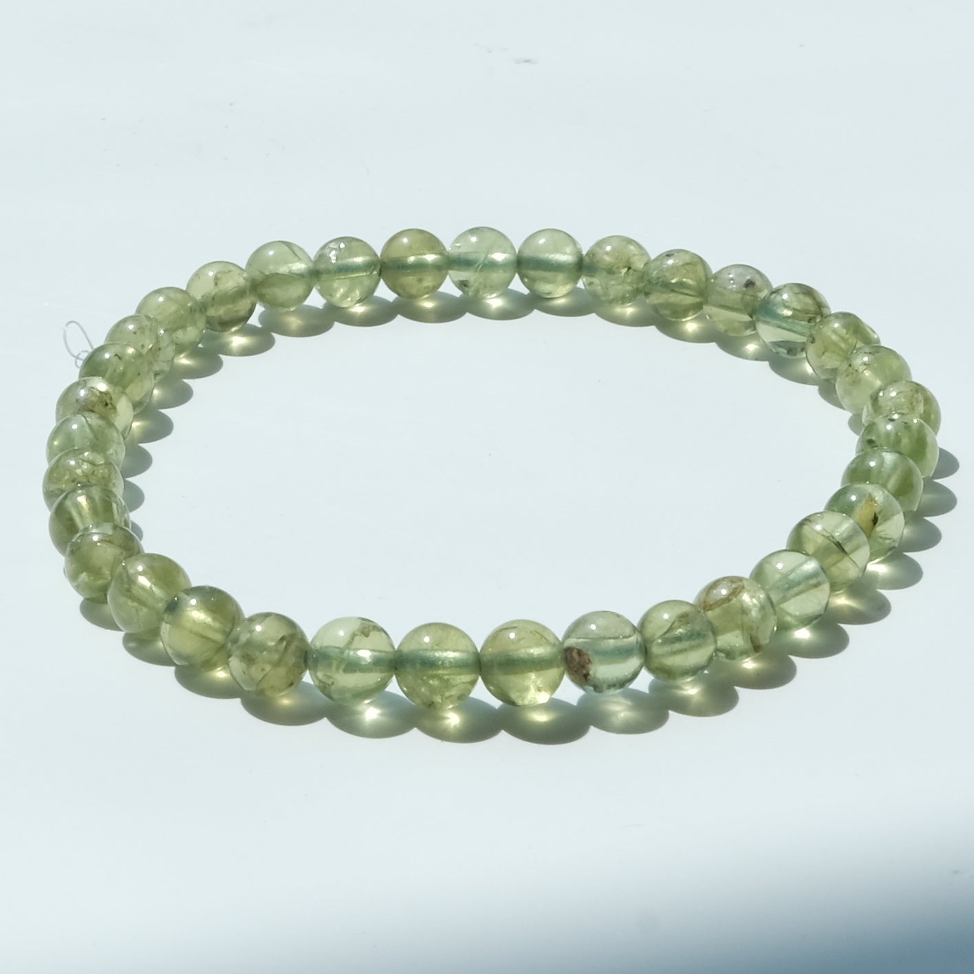 A beaded stretch bracelet made of translucent light green round beads, displayed on a plain white background.