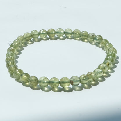 A beaded stretch bracelet made of translucent light green round beads, displayed on a plain white background.