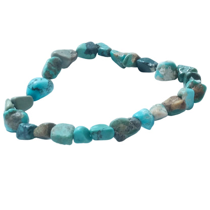 A beaded stretch bracelet made of irregular, polished turquoise-colored stones with natural brown and gray matrix, displayed on a light blue background.